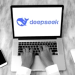 Deepseek aplikacija na laptopu pored mobitela i miša