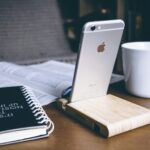 silver iPhone 6 beside white ceramic mug